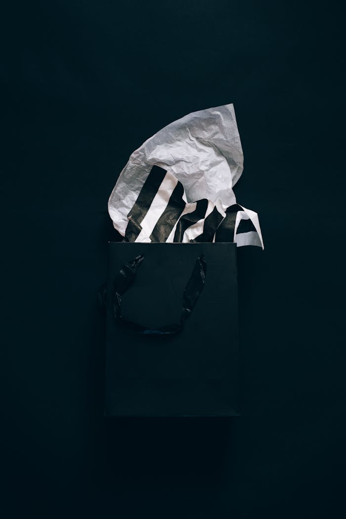our-story-02 Sophisticated black shopping bag with striped tissue paper on dark background, perfect for luxury retail themes.