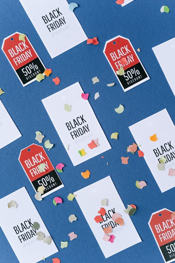 Creative arrangement of Black Friday discount tags with colorful confetti on a blue backdrop, perfect for sales promotion.