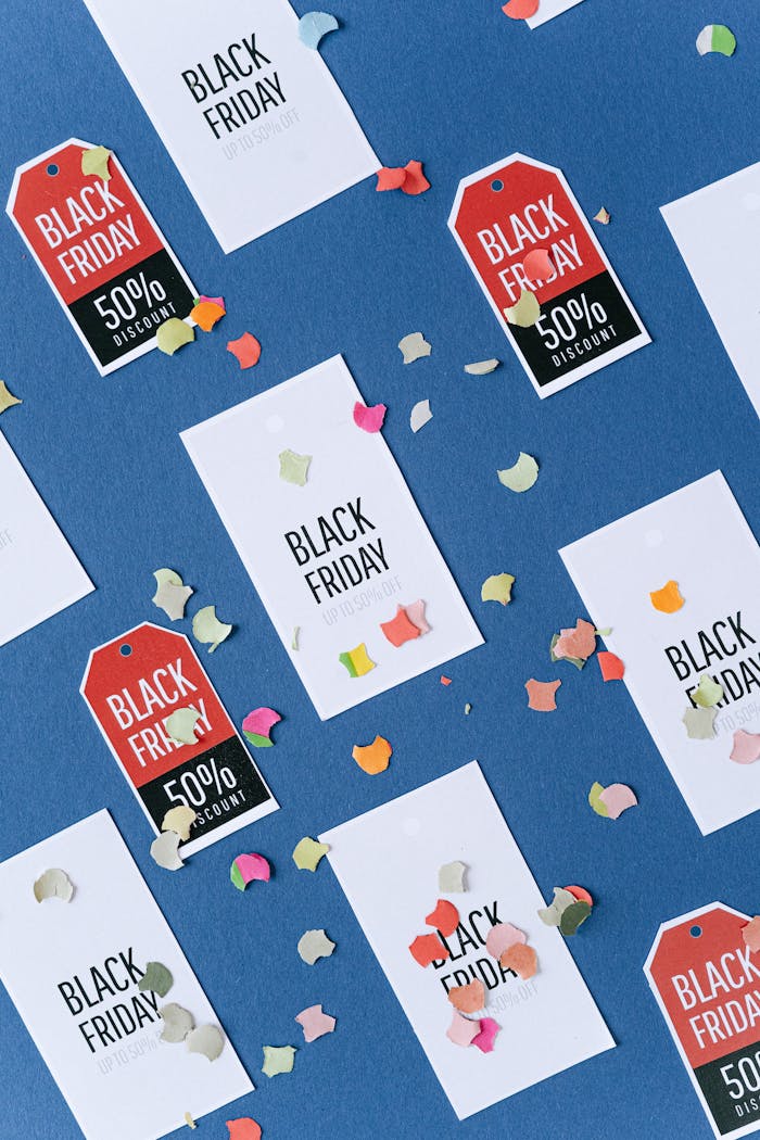 Creative arrangement of Black Friday discount tags with colorful confetti on a blue backdrop, perfect for sales promotion.