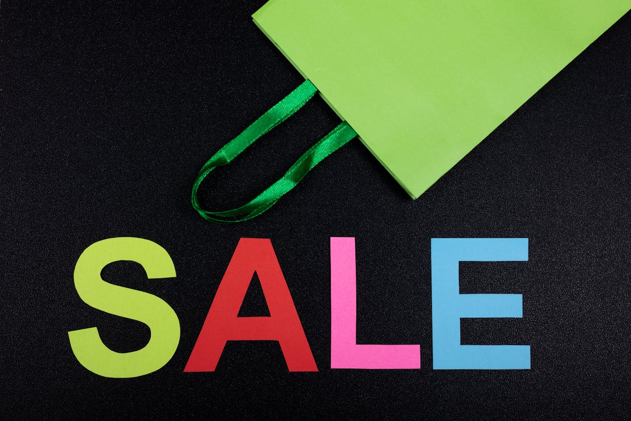 Bright sale text with green shopping bag on black background, perfect for promotions.
